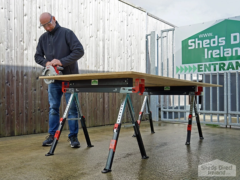A man using a power saw on the saw horse