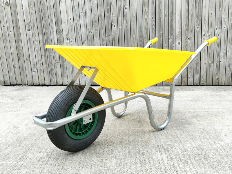 The yellow 90l plastic wheelbarrow against a wooden wall