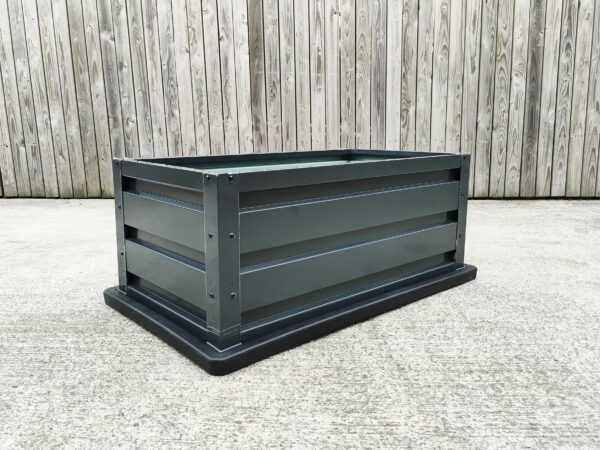 picture of a raised garden bed on a concrete floor with wood behind