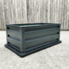 picture of a raised garden bed on a concrete floor with wood behind