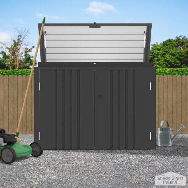 The Carino Storage Unit in a garden. The top door roof is open and there is a lawnmower to the left of it.