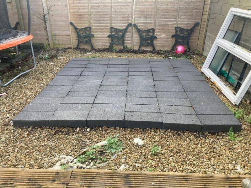 a row of black blocks laid onto grass in a haphazard manner