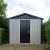 The off-white and black heavy duty shed in a garden.