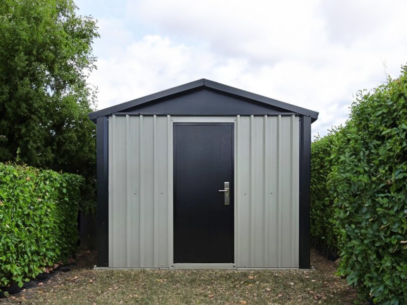 The off-white and black heavy duty shed in a garden.