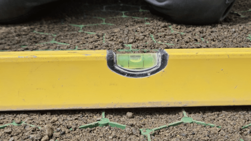 A yellow spirit level with the green bubble centred while sitting on a green shed base