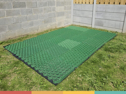 The Shed Base aka 'the eco base' from Sheds Direct Ireland. It's an army-green coloured mesh construction that is sitting on a grassy garden. There is a black membrane under it and there is a grey wall to either side of it.