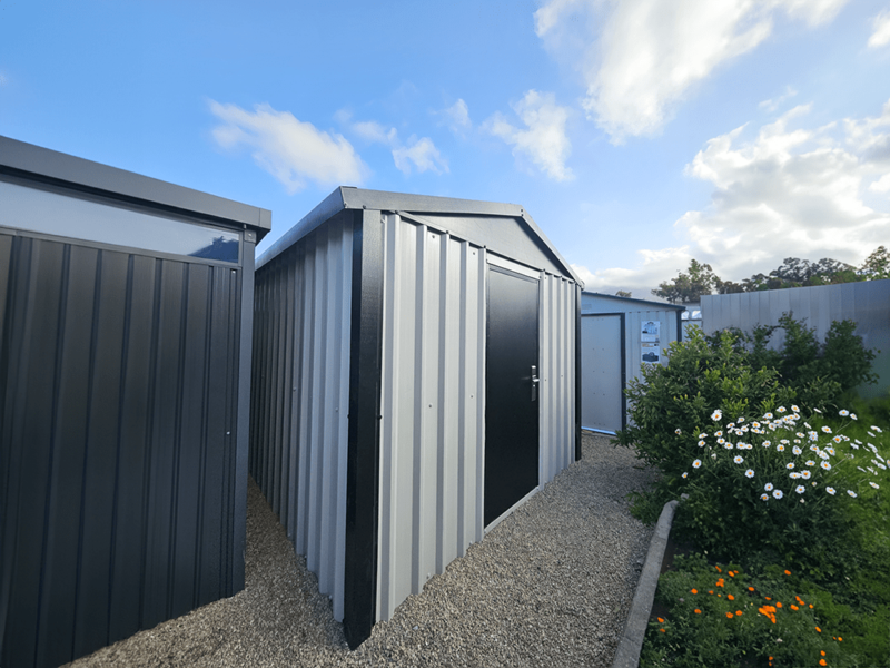 The off-white and black heavy duty shed as seen at a 45 degree angle between two other steel sheds