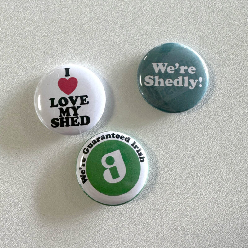 Three button badges that read 'I love my shed', 'we're shedly' and 'We're guaranteed irish!'