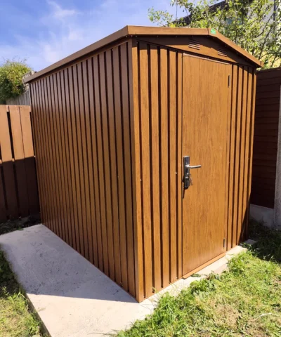 A front-view of the Woodgrain shed with the door closed. It's on a concrete slab in a small garden