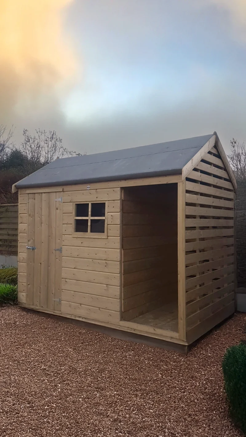 The Log Store in a garden with a yellow-blue sunset behind it