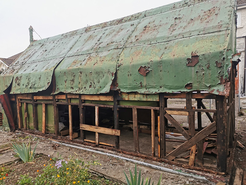A rusted, incomplete, bashed up shed. 
