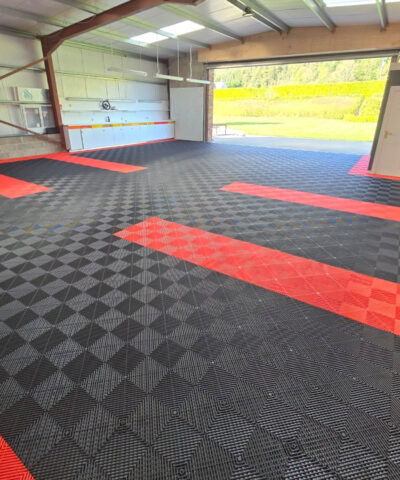 A large garage with the spaced delineated by red flooring