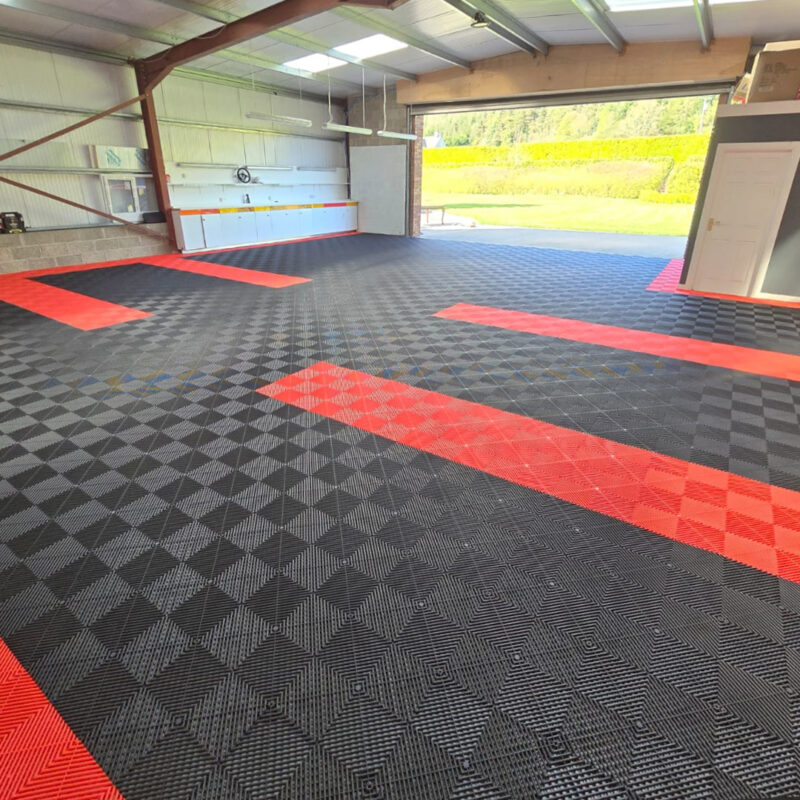 A large garage with the spaced delineated by red flooring