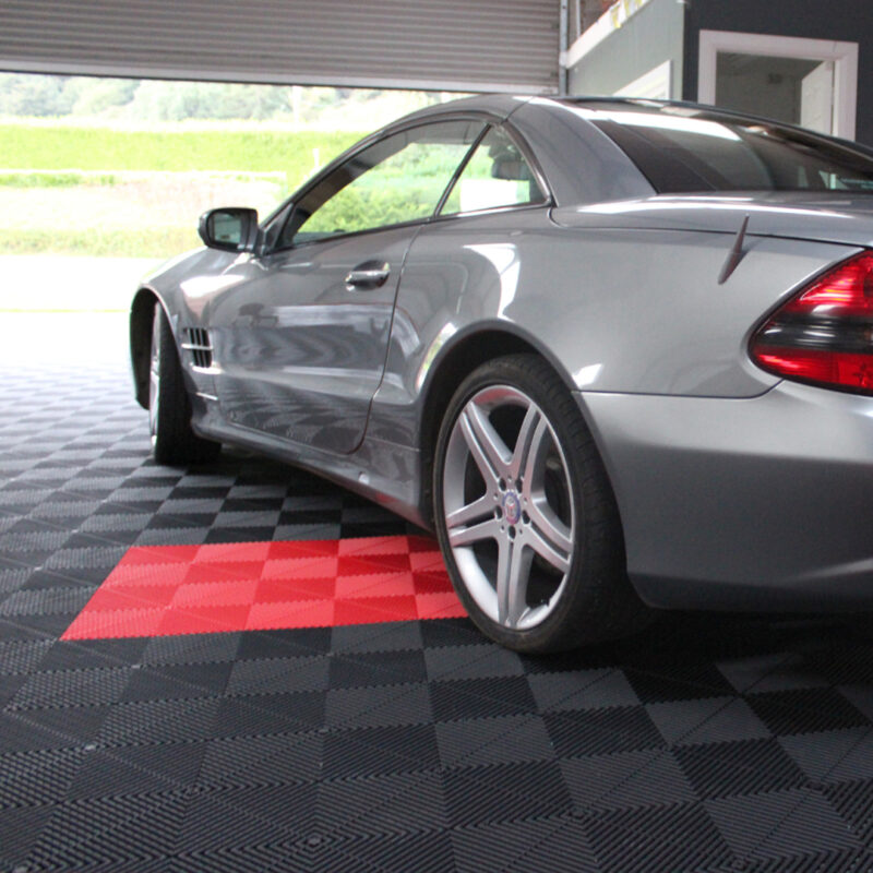 A large garage with the spaced delineated by red flooring