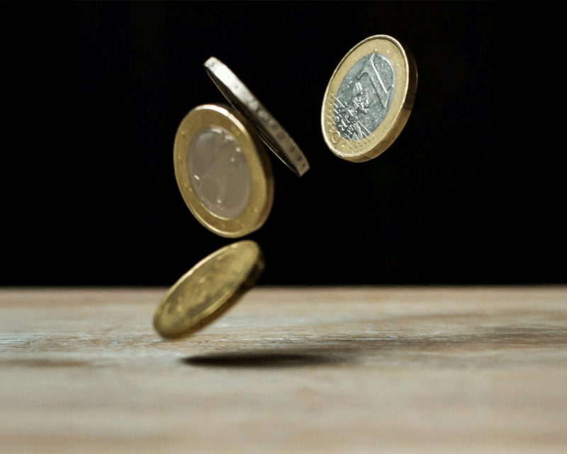 Four €1 coins falling onto a table