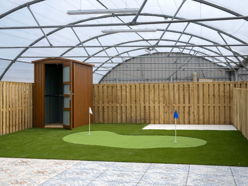 A woodgrain garden shed sitting on artificial grass