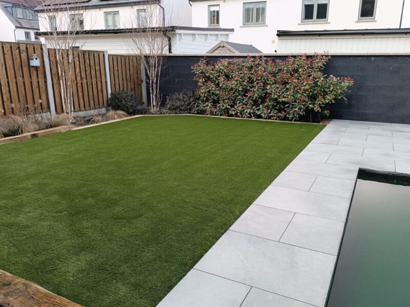 Artificial grass in a garden with a pond