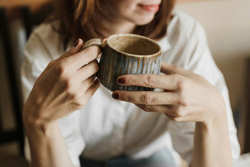 A woman drinking tea from a ceramic cup